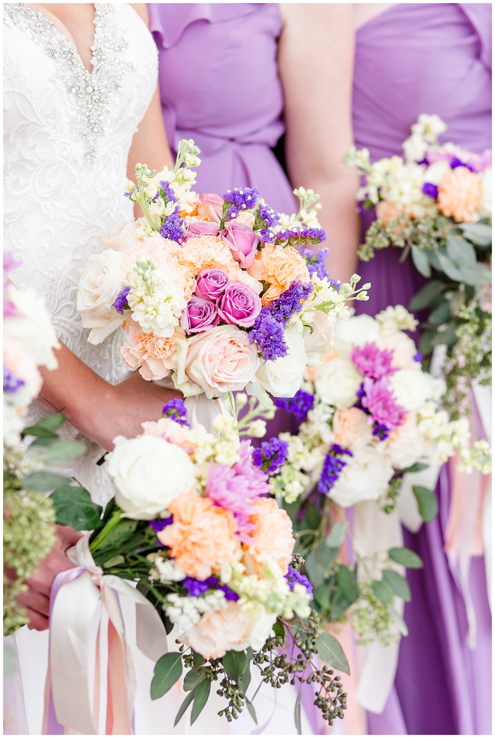 Purple, gold, and orange wedding bouquets with ribbon and purple bridesmaid dresses