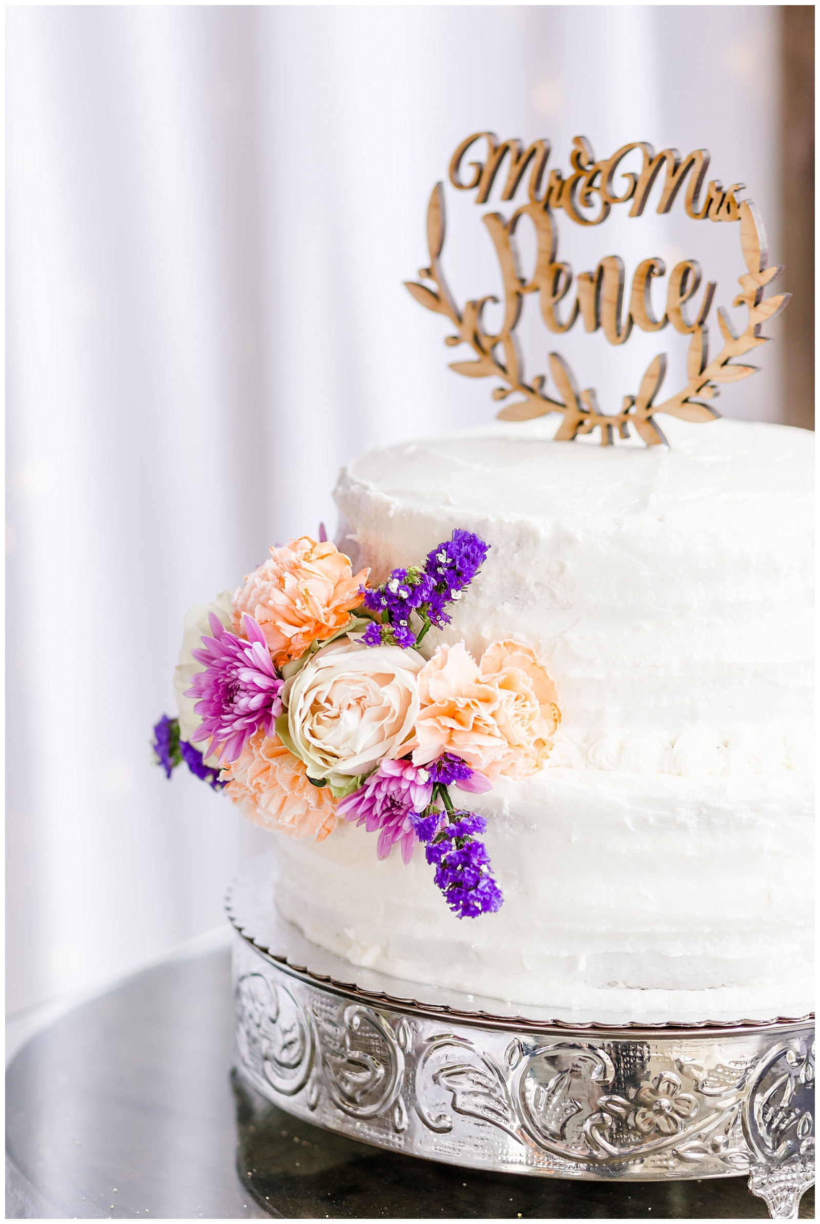Simple white wedding cake with purple and orange flowers and gold details