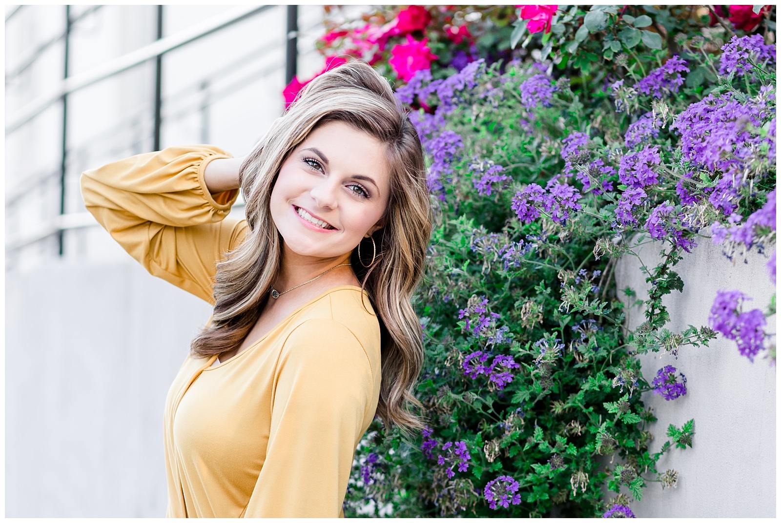 Downtown city senior portrait session in white jeans and a mustard yellow top with a marble building and flowers