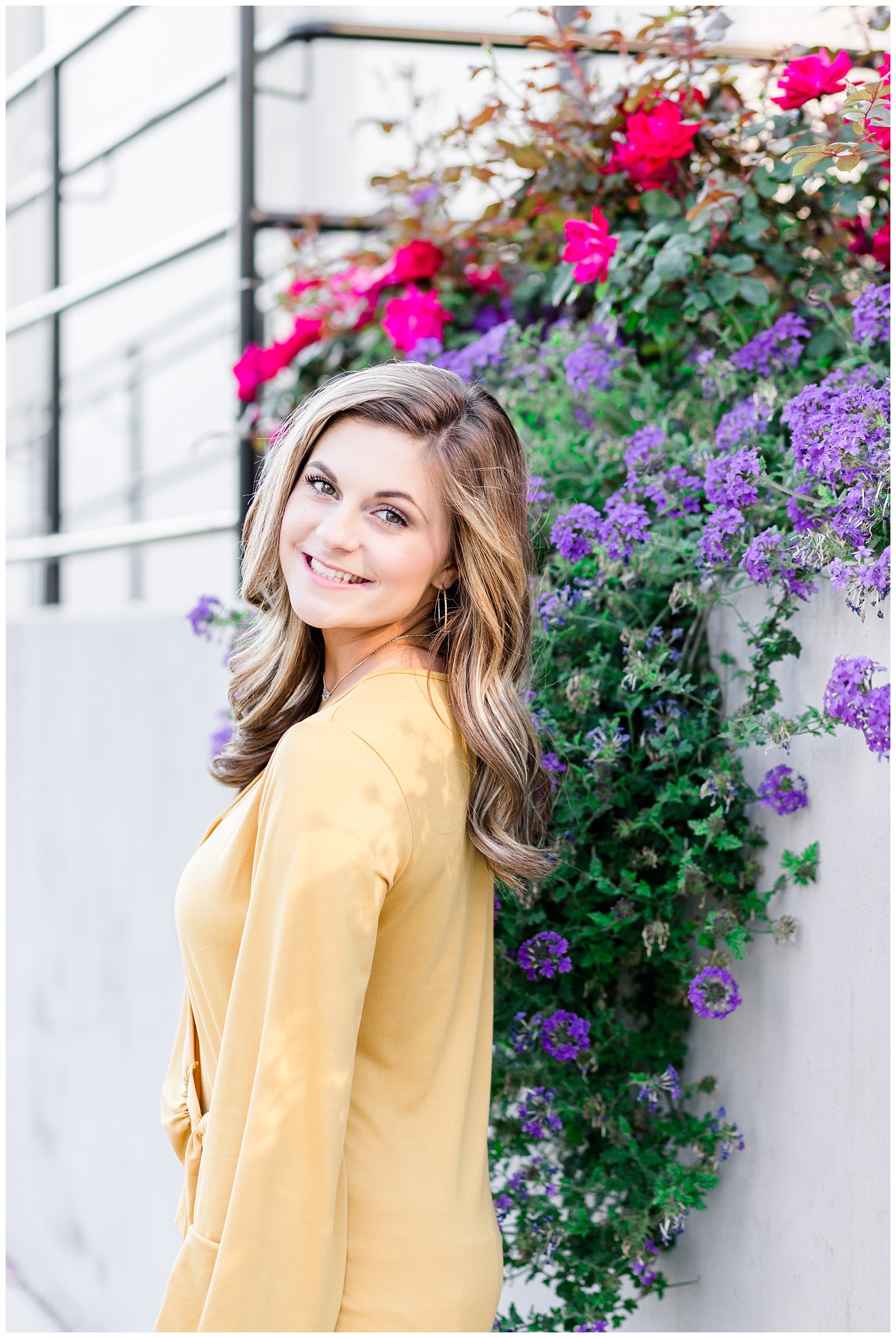 Downtown city senior portrait session in white jeans and a mustard yellow top with a marble building and flowers