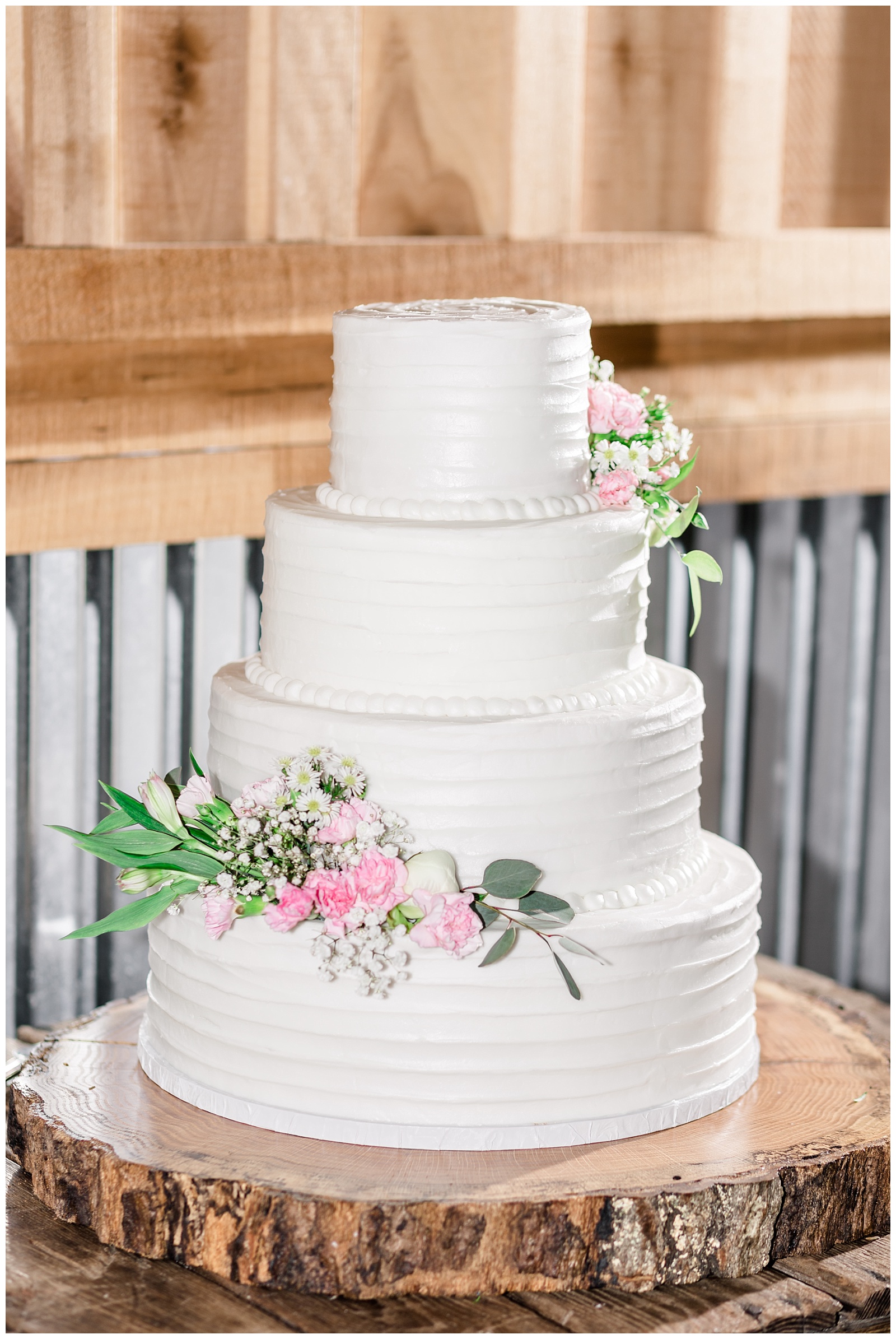 white wedding cake with pink floral design at rustic alabama barn wedding