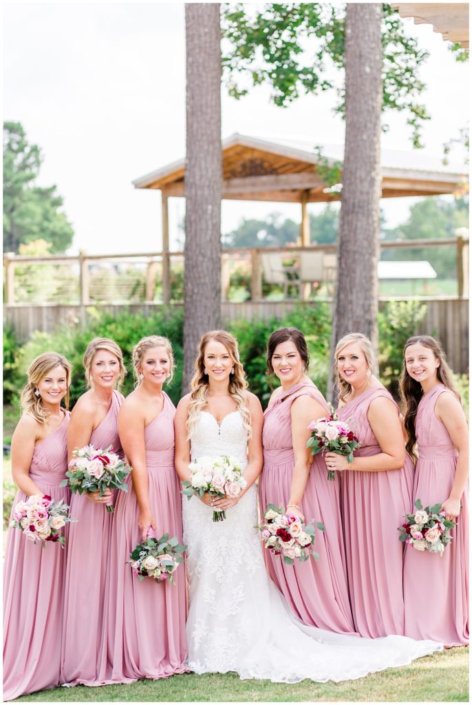 wine and pink wedding photo with bridesmaids in pink dresses and pink and white bouquets