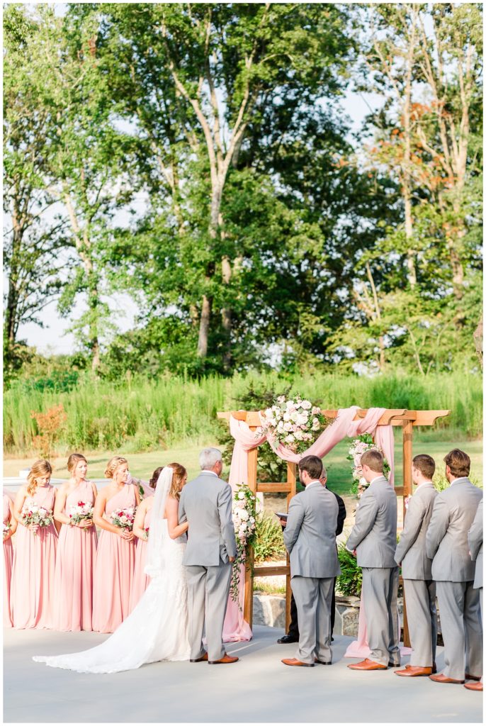 wedding arbor with pink cloth and white, pink, and wine florals