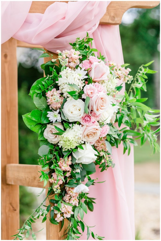 white and pink wedding florals on arbor