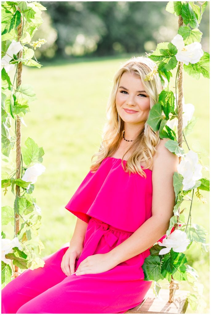 summer senior session on swing in pink jumpsuit