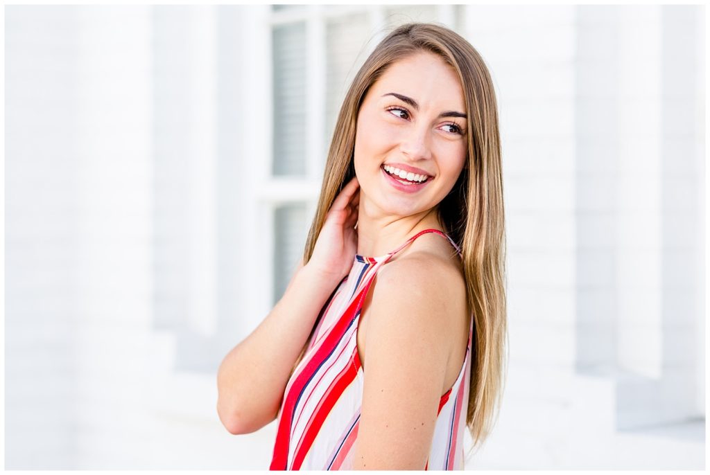downtown senior session in front of white wall with girl in bright striped top