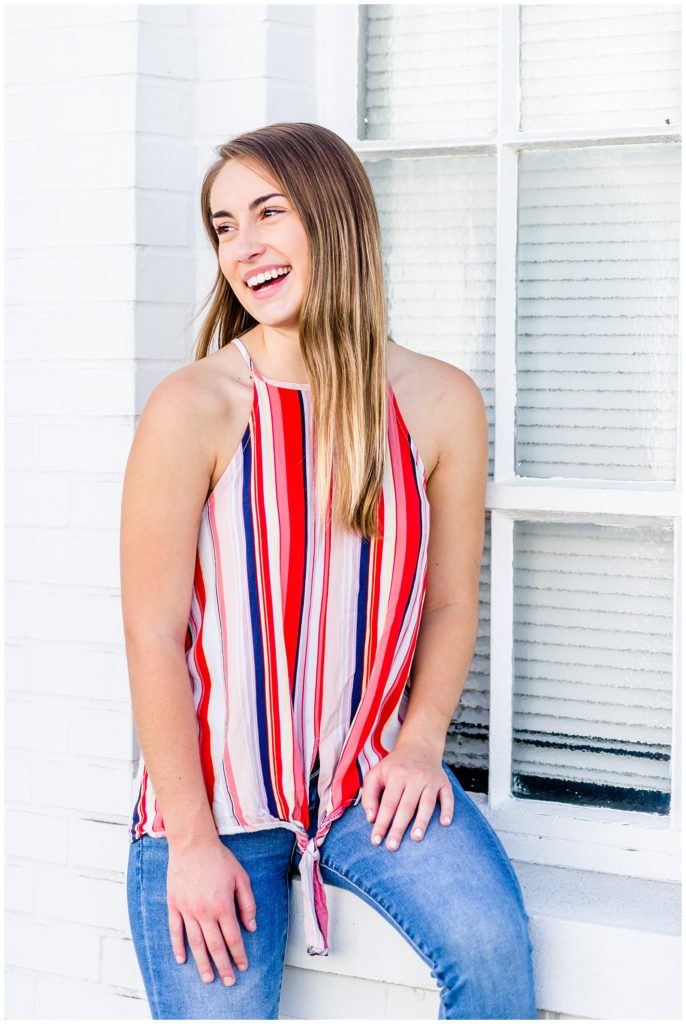 downtown senior session in front of white wall with girl in bright striped top