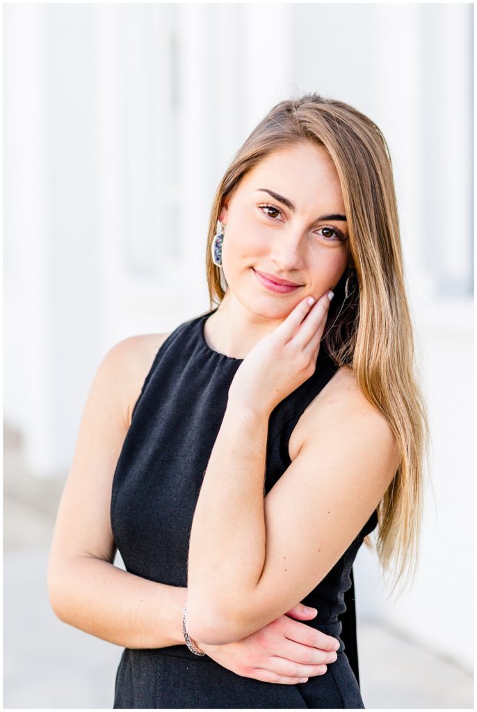 downtown senior session in front of white wall with girl in black romper