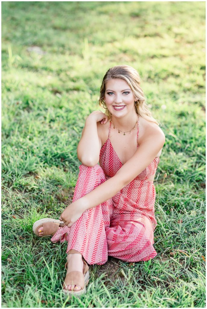 boho senior session with bright red couch, and red barn, and sunflowers