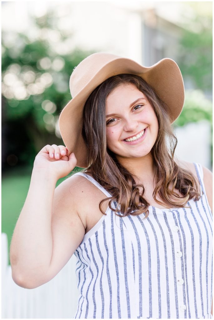 summer downtown senior session in blue striped jumpsuit and floppy hat