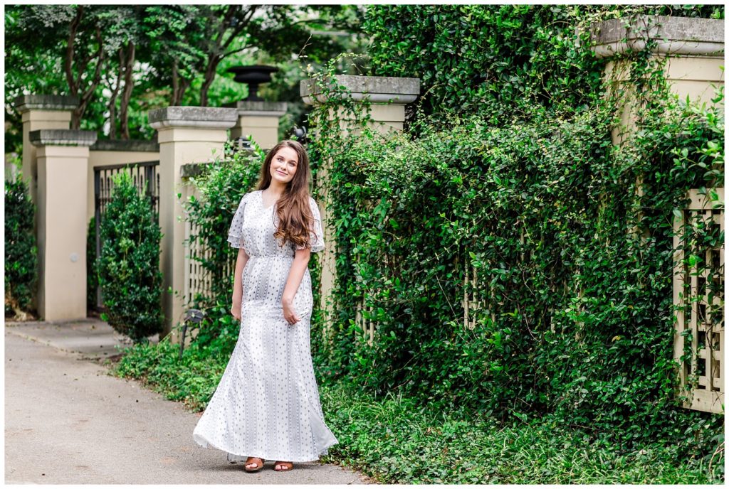 downtown senior session photo in maxi dress with wall covered in greenery