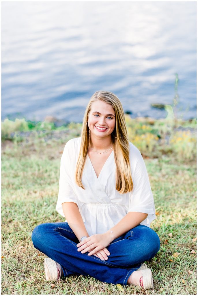 lake senior session photo of girl in white top and bell bottom jeans