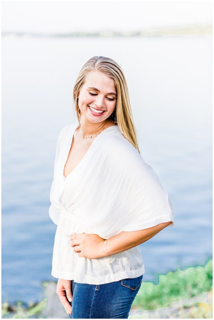 lake senior session photo of girl in white top and bell bottom jeans