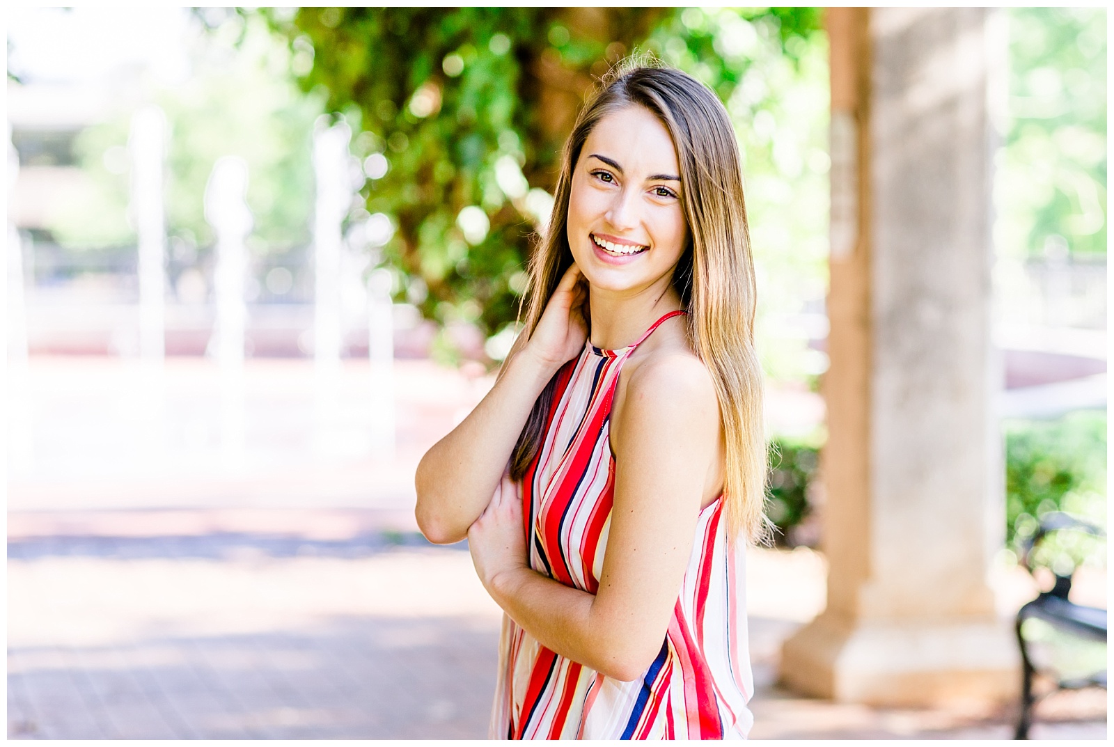 downtown senior session in front of greenery covered arch with girl in bright striped top