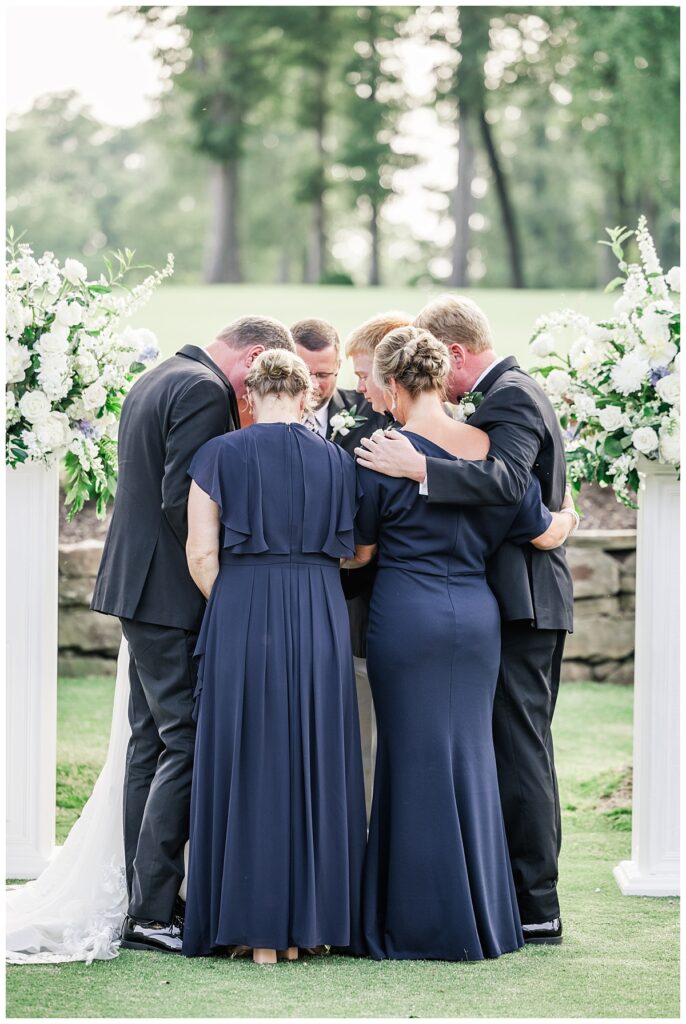 family praying with bride and groom at wedding ceremony at the ledges club