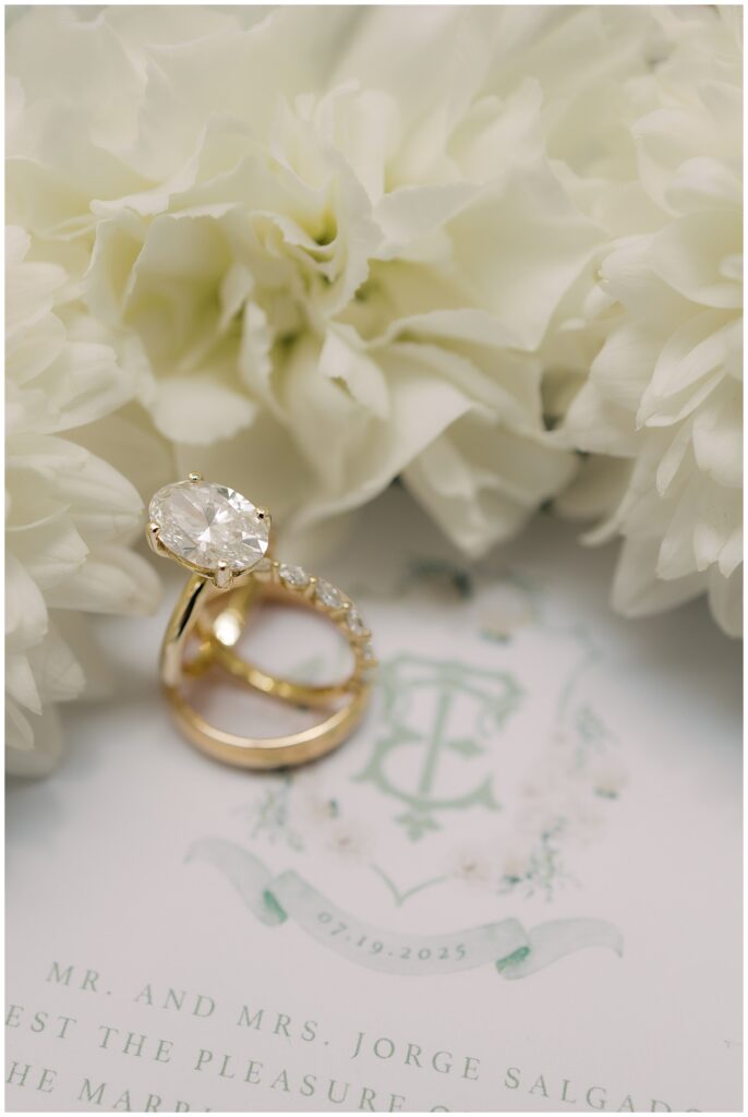 gold engagement ring and wedding bands with sage wedding crest invitation