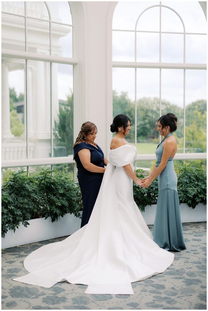 bride getting ready photos with mom and sister in sage dresses